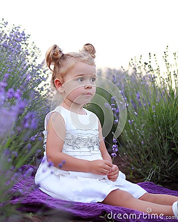 Girl in a white dress walks in a lavender field at sunset Stock Photo