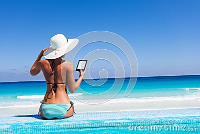 Girl with white hat reads kindle on beach Stock Photo