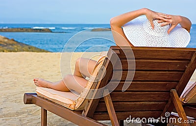 Girl in white hat sitting in chaise longue Stock Photo