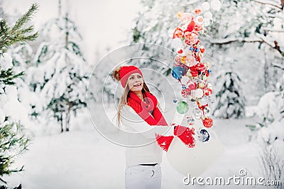 A girl in a white jacket throws Christmas balls to decorate the Christmas tree.A girl throws Christmas decorations from Stock Photo