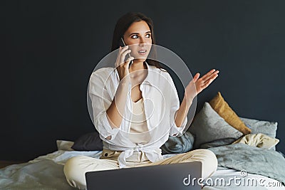 Girl in white shirt expresses surprise while talking on phone. Stock Photo