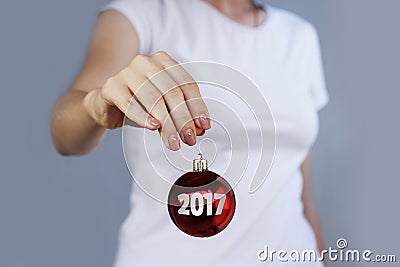 Girl in white t-shirt holding Christmas toy red ball with inscription 2017. Stock Photo