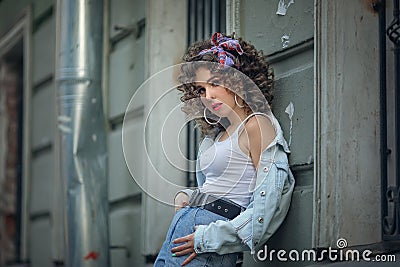 A girl in a white t-shirt and jeans leaned against the wall Stock Photo