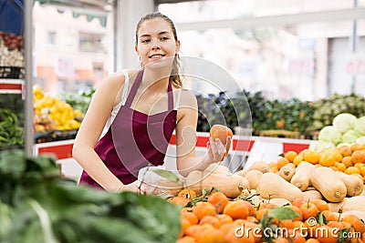 Girl salesperson in a store puts the tangerines on the counter Stock Photo