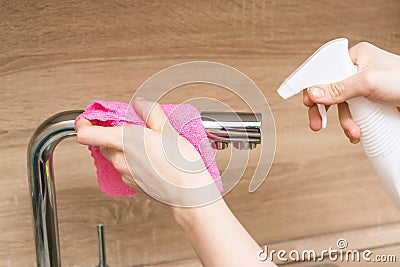 girl wipes the sink faucet with a rag Stock Photo