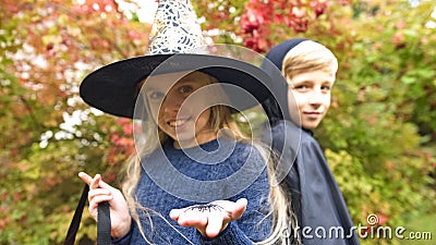 Girl in witch costume holding scary spider and boy-vampire posing for camera Stock Photo