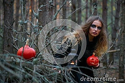 Girl witch witch pumpkin on halloween in a dark pine forest Stock Photo