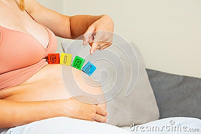 Girl word made of toy blocks on big pregnant belly Stock Photo