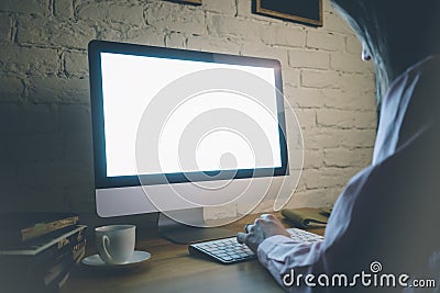 He girl working behind a computer keyboard and looking at the blank monitor with blue screen on your wooden table against a white Stock Photo