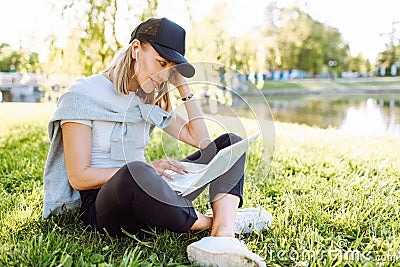 Girl working at the computer sittingon the grass in a protective medical mask on her face. Freelance, quarantine concept Stock Photo