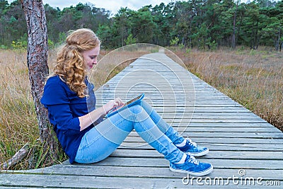 Girl working on tablet computer on path in nature Stock Photo