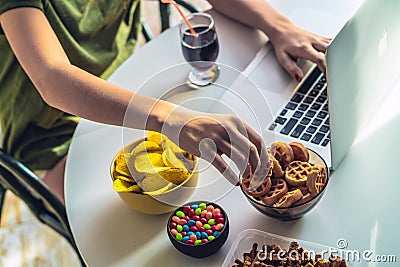 Girl works at a computer and eats fast food. Stock Photo
