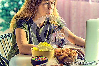 Girl works at a computer and eats fast food. Stock Photo