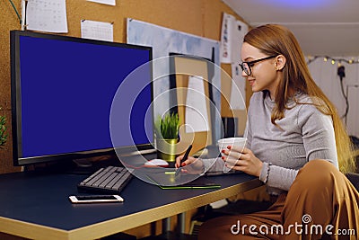 Girl works at home, graphic tablet, girl looks at a computer, green screen. Stock Photo