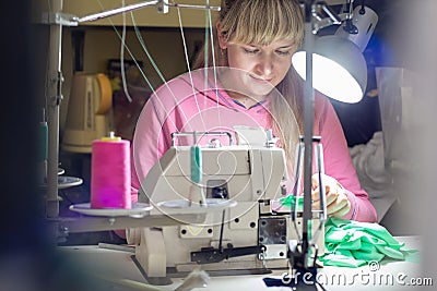 Girl works by light lamp behind industrial sewing machine Stock Photo