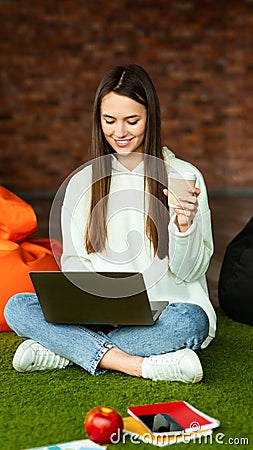 Girl in workspace working on laptop and drinking coffee Stock Photo