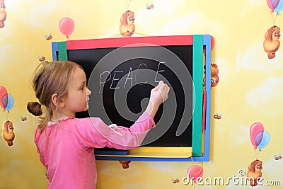 The girl writes on a blackboard a word the peace Stock Photo