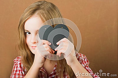 The girl writes a love message on Valentine`s Day. Baby with heart close-up and copy space. Children`s hands write a love message Stock Photo