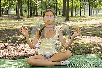 girl& x27;s happy and Meditate on the practice of yoga in the park , yoga kid. Healthy lifestyle - little girl doing yoga in the Stock Photo