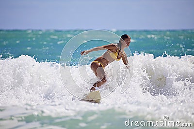 Girl in a yellow bikini surfing Stock Photo