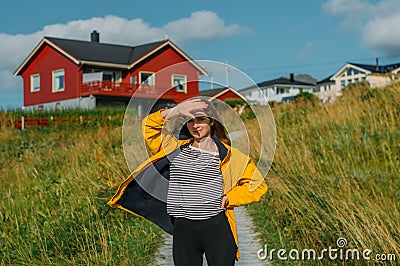 Girl in yellow jacket on the pathway to houses on Lofoten Islands Stock Photo