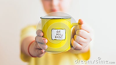 A girl with a yellow cup in her hand, on which was written Did you know Stock Photo