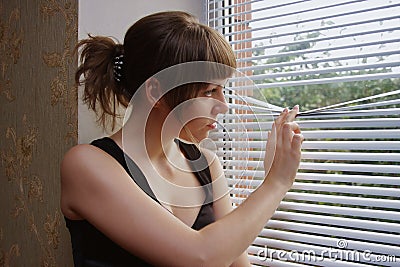 A girl is young looks through a window Stock Photo