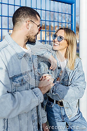 Girlfriend and boyfriend clutching the fence looking each other and touching her hands. Happy couple Stock Photo