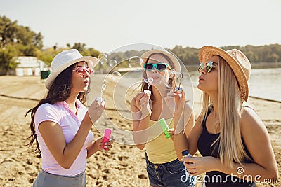 Girlfriends blowing soap bubbles on the beach. Stock Photo