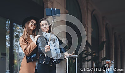 Girlfriends tourist taking photo selfie together on smartphone mobile. Blogger hipster travels in europe city hotel. Vacation Stock Photo