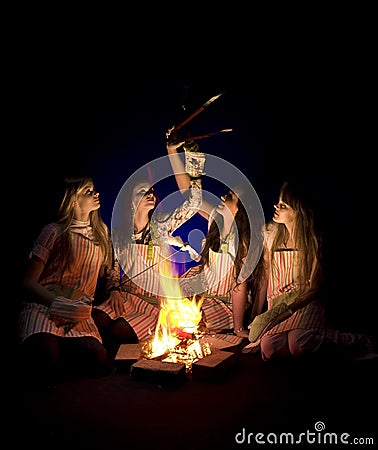 Girls in aprons by campfire Stock Photo
