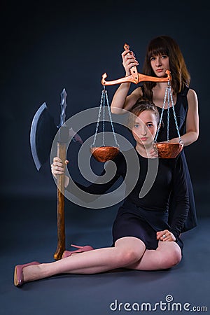 Girls as guardians of law, justice and rights, holding in their hands the scales and the ax as instrument of retaliation Stock Photo