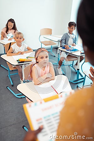 Girls and boy looking and listening to their teacher Stock Photo