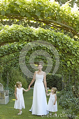 Girls And Bride Walking Under Ivy Arches Stock Photo