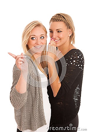 Girls chat - woman whispers on friends ear Stock Photo