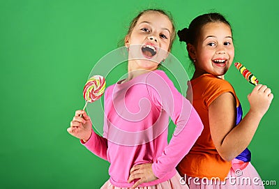 Girls with cheerful faces pose with candies on green background. Stock Photo