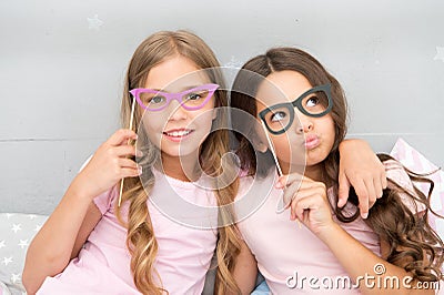 Girls children posing with grimaces photo booth props. Pajamas party concept. Girls friends having fun pajamas party Stock Photo