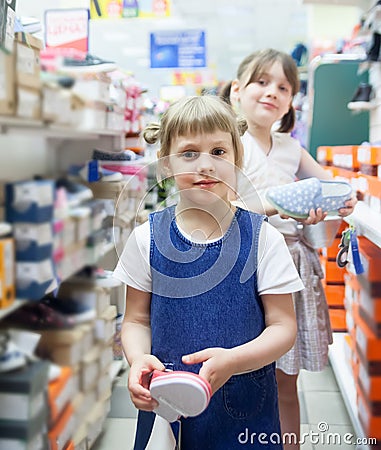 Girls choosing summer shoes in store. Stock Photo