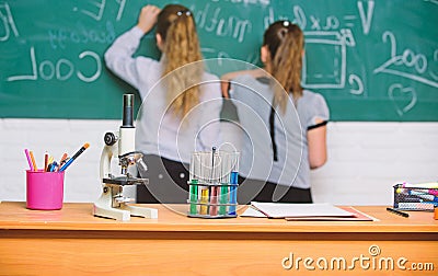 Girls classmates study chemistry. Microscope and test tubes on table. Chemical reactions. Make studying chemistry Stock Photo