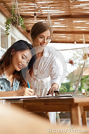 Girls At Coffee Shop. Women With Laptop Having Discussion About Business. Beautiful Colleagues In Casual Clothes Working Stock Photo