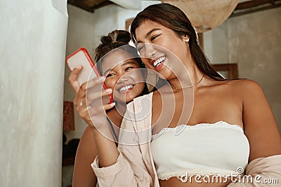 Girls Doing Selfie. Friends Using Smartphone For Taking Photo. Young Women Looking At Digital Device Screen And Smiling. Stock Photo