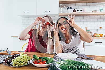 Girls fooling around in the kitchen playing with vegetables. Stock Photo