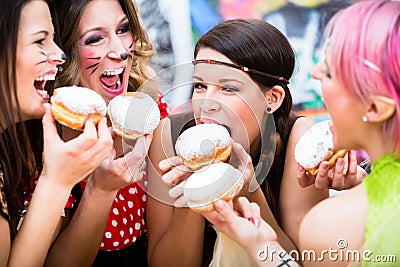 Girls at German Fasching Carnival eating doughnut-like traditional pastry Stock Photo