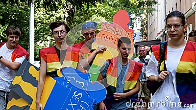 Girls and guys in rainbow vests carry a cardboard figure of a man with the inscription Undo sexism. Editorial Stock Photo