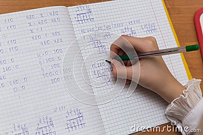 A girls hand with a fountain pen solves examples in mathematics close-up. Stock Photo