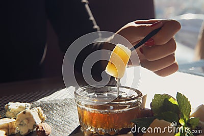 Girls hand with a piece of parmesan. Honey flowing . Stock Photo