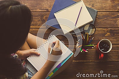 Girls are pen to write on the notebook on wood floor Stock Photo