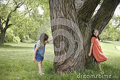 Girls Playing Hide And Seek By Tree Stock Photo