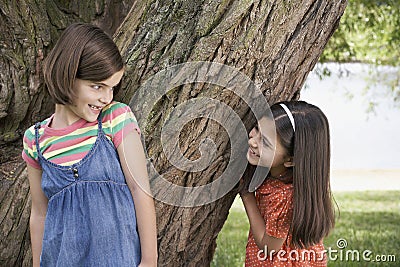 Girls Playing Hide And Seek By Tree Stock Photo