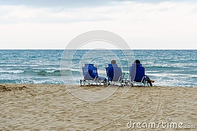 Girls sit on the deck chairs and look at the sea Stock Photo